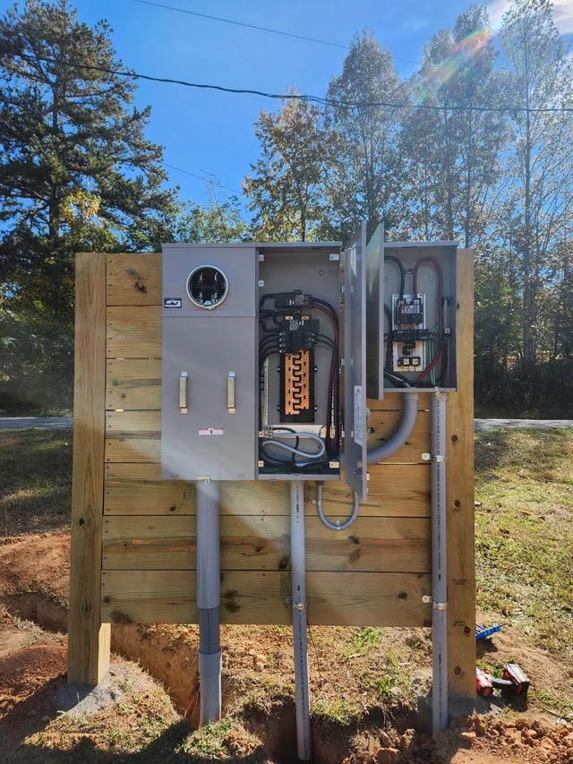 Outdoor meter and breaker panel with the cover open, mounted on a wooden post
